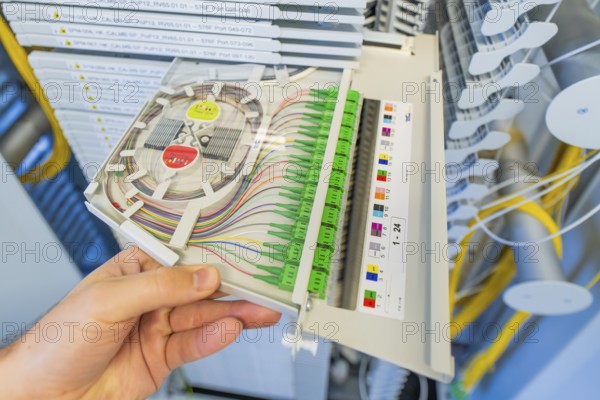 Close-up of a hand holding a fiber optic cabling module, optical fiber