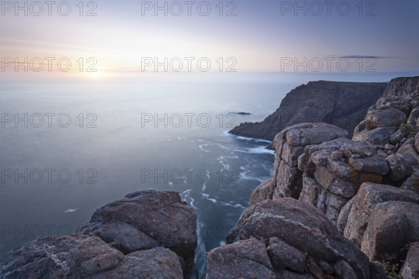 Long exposure shows sunset over the cliffs of Cape Raoul. Golden light hits the sea and colors the rocks warmly in the evening. Cape Raoul, Tasman Peninsula, Tasmania, Australia