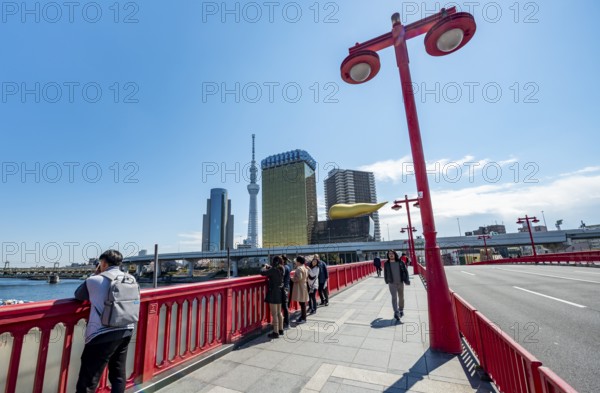 Visitors on the Azuma Bridge, Sumida City Skyline, Sumida City Office, Tokyo Skytree, Asahi Beer Hall and Asahi Headquarters with Asahi Flame, Asakusa, Tokyo, Japan