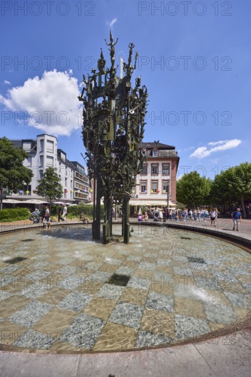 Shrove Tuesday fountain, fountain with bronze sculptures, sculptor Blasius Spreng, architect Helmut Gräf, general architecture, houses, pedestrians and seated people as secondary motifs, trees, blue sky, cumulus clouds, Schillerplatz square, Mainz, state capital, district-free city, Rhineland-Palatinate, Germany