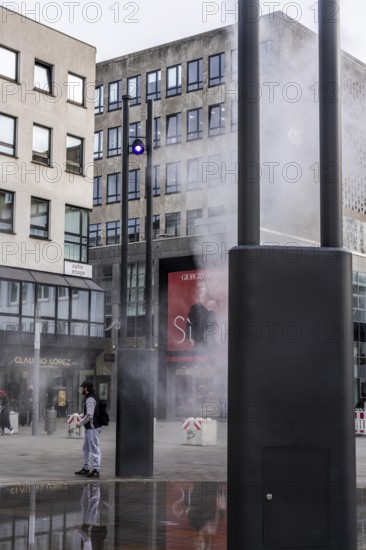 Digital water feature, Blue Cloud water installation on Husemanplatz in downtown Bochum, water mist is sprayed from 4 metal masts, which, in conjunction with the circular water surface, is intended to cool the surrounding area when it is hot, colored light images are projected into the water mist via projectors, part of the transformation of Husemanplatz