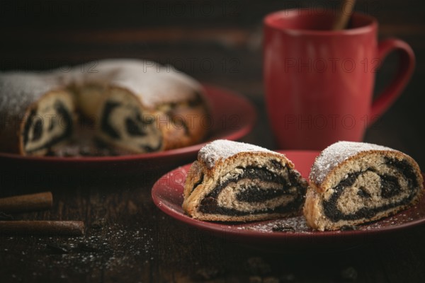 Poppy seed cake with red crockery and cinnamon sticks on wooden background