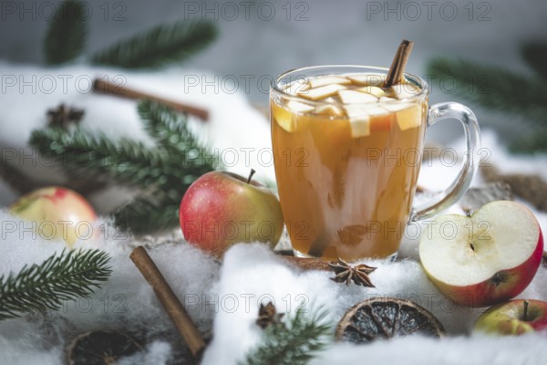 A glass of apple punch and apple pieces in a wintery setting