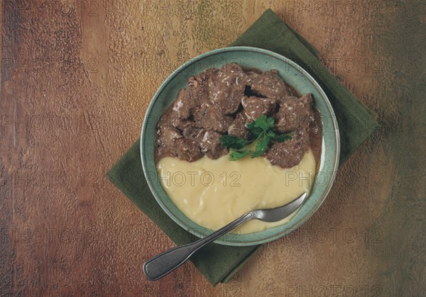 Liver beef stroganoff with mashed potatoes, table setting in green tones, homemade
