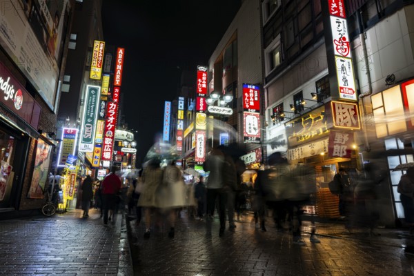 Busy pedestrian zone with many shopping centers and stores, illuminated with lots of neon signs at night, Shibuya, Udagawacho, Tokyo, Japan