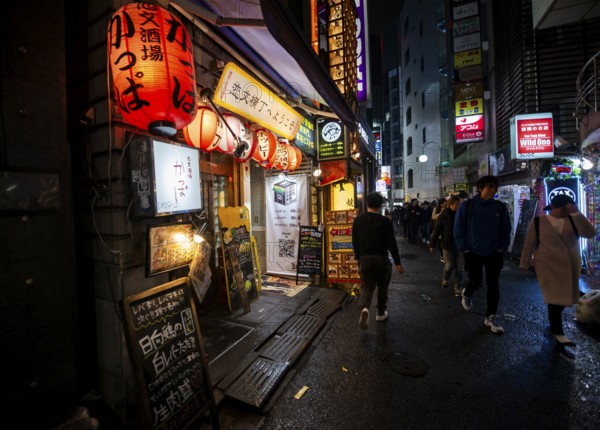 Pedestrians, alley with neon signs, paper lanterns and advertising signs at night, Udagawacho, Shibuya, Tokyo, Japan