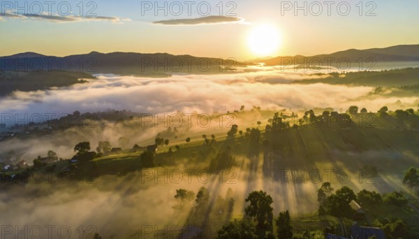 Sunrise over a fog covered village in a rural landscape, golden morning light, serene autumn atmosphere, hills and mountains in the background, AI generated