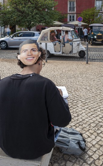 Street art, young people with Ronaldo mask on the back of their heads taking part in a school project about drawing, Lisbon, Portugal