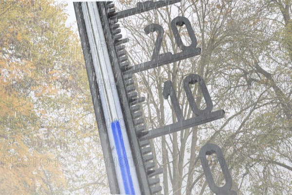 (photo montage) Thermometer in front of autumn-colored deciduous tree shows cool temperatures