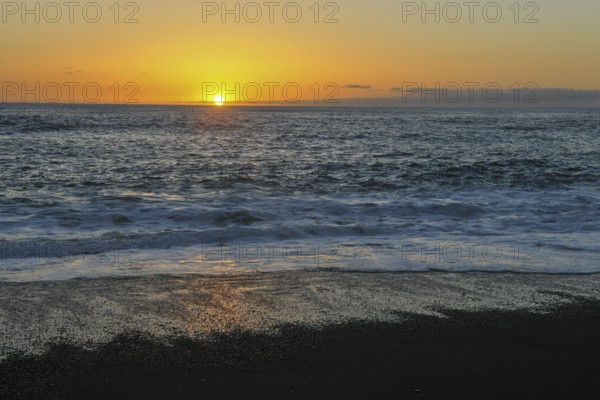 Idyllic sunset on calm calm seas of the eastern Atlantic Atlantic with gentle waves on lava beach, Lanzarote, Canary Islands, Spain