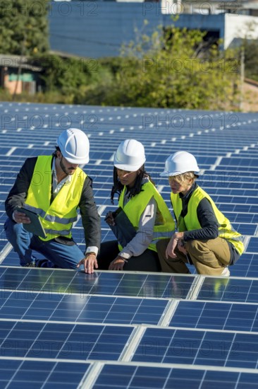 Diverse team of engineers and technicians inspecting and discussing solar panel installation and maintenance at a modern, sunlit solar farm focused on sustainable clean energy generation
