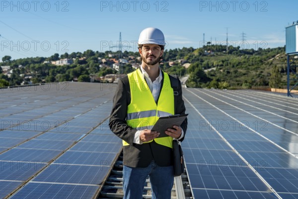 Engineer in hard hat and safety vest standing on a rooftop of solar panels holding a clipboard, inspecting photovoltaic array and representing renewable, sustainable power generation