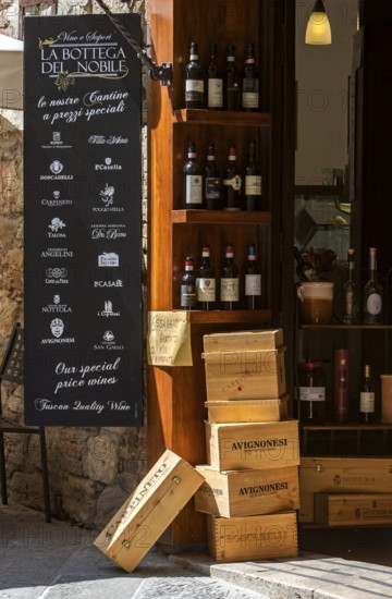 Italian wine shop with wine bottles and wooden boxes in rustic surroundings, Tuscany, Italy