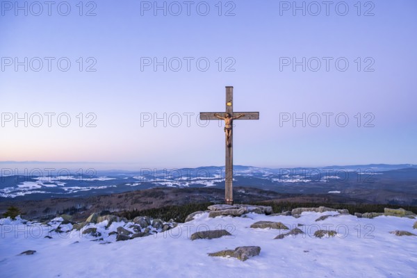 Christian cross on the peak of Mount Lusen with the view over the hills of the bavarian forest at sunrise at winter, Bavaria, Germany