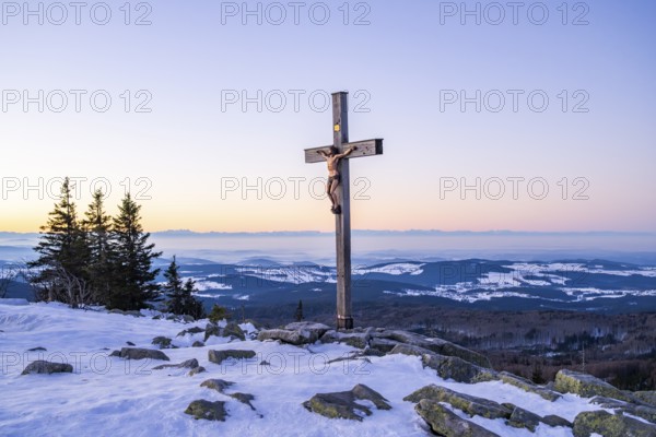 Christian cross on the peak of Mount Lusen with the view over the hills of the bavarian forest at sunrise at winter, Bavaria, Germany