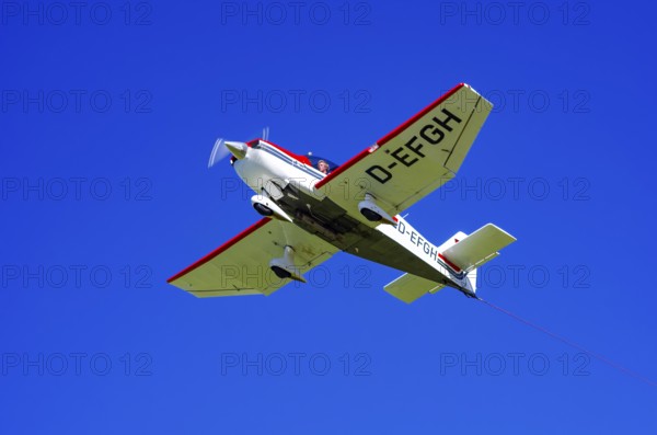 A Robin DR 400/200R Remorqueur light aircraft, registration D-EFGH, tows a glider during a flight demonstration as part of an air show on Rossfeld in Metzingen-Glems, Baden-Württemberg, Germany, for editorial use only