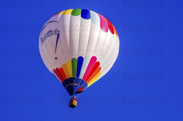 A hot air balloon, registration D-OÖJ, rises into the air as part of an air show at the Fliegerbergfest of the Rossfeld Luftsportverein in Metzingen-Glems, Baden-Württemberg, Germany, for editorial use only