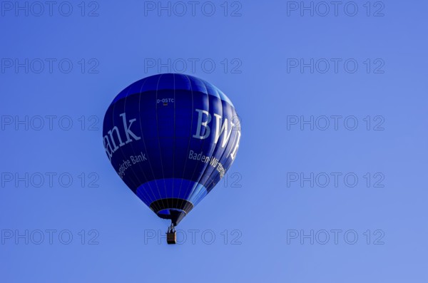 A hot air balloon, registration D-OSTC, rises into the air as part of an air show at the Rossfeld Air Sports Association's Flying Festival on Rossfeld in Metzingen-Glems, Baden-Württemberg, Germany, for editorial use only