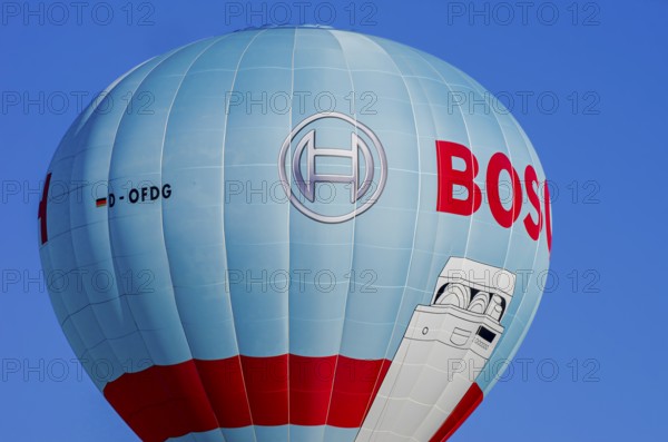 A hot air balloon, registration D-OFDG, rises into the air as part of an air show at the Fliegerbergfest of the Rossfeld Luftsportverein in Metzingen-Glems, Baden-Württemberg, Germany, for editorial use only