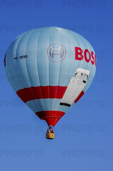 A hot air balloon, registration D-OFDG, rises into the air as part of an air show at the Fliegerbergfest of the Rossfeld Luftsportverein in Metzingen-Glems, Baden-Württemberg, Germany, for editorial use only