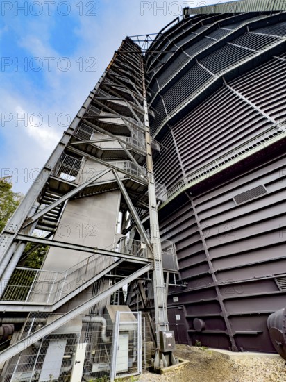 View steeply upwards on the outside with left external staircase of former Gasometer Oberhausen today exhibition venue, North Rhine-Westphalia, Germany