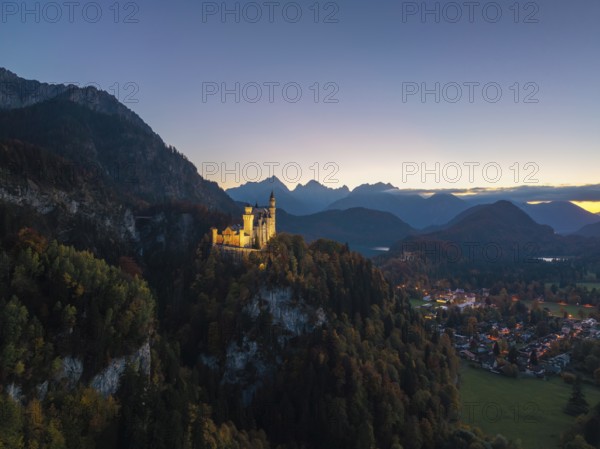 Majestic Neuschwanstein Castle at dusk, surrounded by mountains and forests, romantic lighting, Schwangau near Füssen, Ostallgäu, Allgäu, Bavaria, Germany