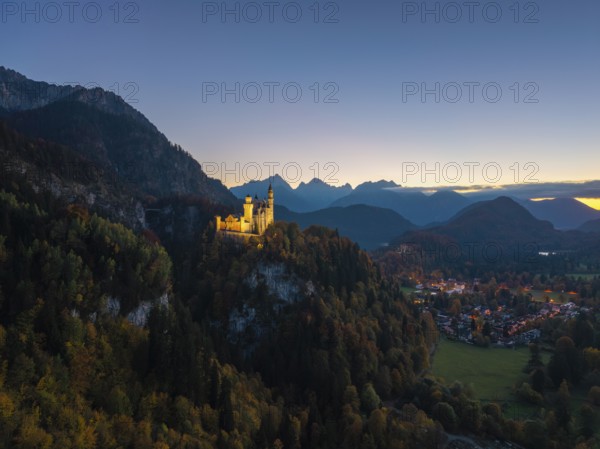 Neuschwanstein Castle on a hill in wooded surroundings with impressive mountain panorama, Schwangau near Füssen, Ostallgäu, Allgäu, Bavaria, Germany