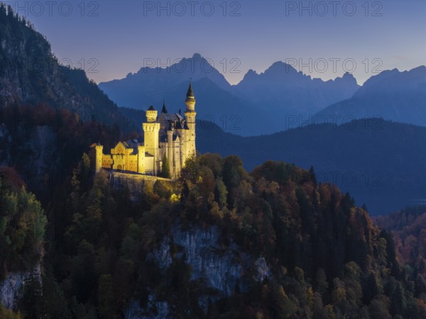 Sublime illuminated Neuschwanstein Castle on a ridge in the midst of an alpine landscape at sunset, Schwangau near Füssen, Ostallgäu, Allgäu, Bavaria, Germany