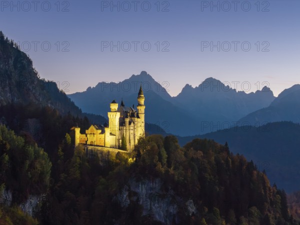Neuschwanstein Castle at dusk with mountain views and surrounded by forest