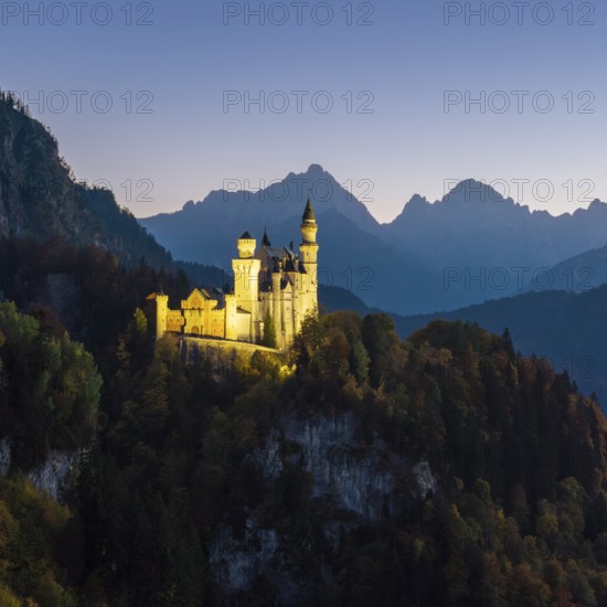 Illuminated Neuschwanstein Castle at dusk against a mountain backdrop, Schwangau near Füssen, Ostallgäu, Allgäu, Bavaria, Germany