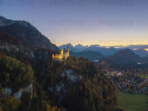 Neuschwanstein Castle stands illuminated on a hill, surrounded by mountains and a natural panorama, Schwangau near Füssen, Ostallgäu, Allgäu, Bavaria, Germany