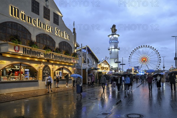 Oktoberfest visitors with umbrellas, rainy meadows, Löwenbräuturm, Ferris wheel, Munich, Bavaria, Germany