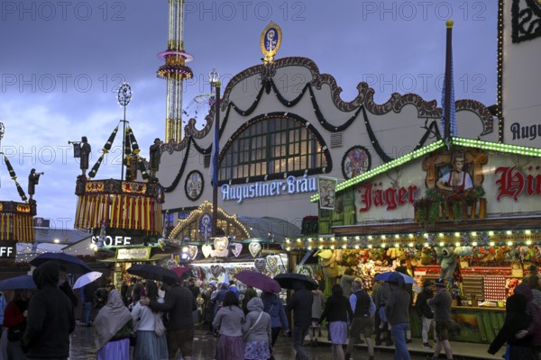 Oktoberfest visitors with umbrellas, rainy meadows, Augustiner festival tent, Munich, Bavaria, Germany