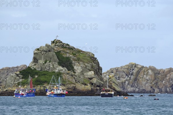 Small boats on the sea surrounded by rough rocky coast, Isles of Scilly, Cornwall, Great Britain