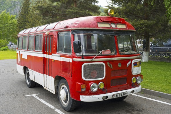 Red retro bus in a parking lot surrounded by trees and green nature, PAZ-672, minibus from Soviet manufacturer Pavlovsky, Jermuk, Jermuk, Vayots Dzor province, Armenia