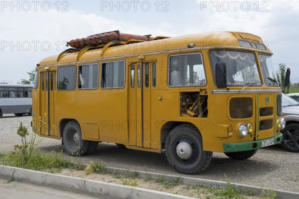 Vintage yellow bus on a road surrounded by a meadow, under cloudy sky, PAZ-672, minibus from Soviet manufacturer Pavlovsky, gas drive, Khor Virap, Ararat province, Armenia