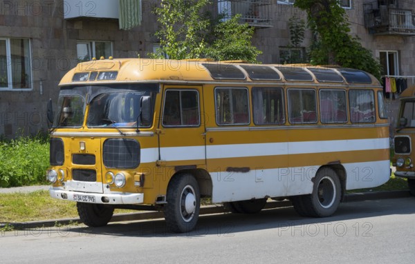 An old retro bus in orange parked on a street next to a building, PAZ-672, minibus from the Soviet manufacturer Pavlovsky, Armenia