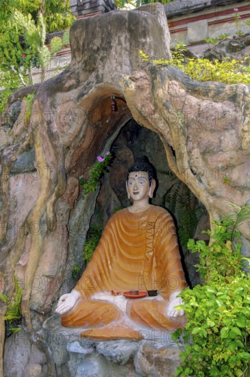 Statue figure of sitting Buddha in artificial grotto with hands shaped into thumb and index finger sculpting Jnana Mudra Gyan Mudra, Brahma Vihara Brahmavihara Arama Buddhist Monastery, Banjar, Bali, Indonesia