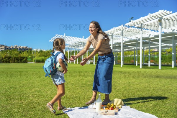 Mother and daughter enjoying a happy summer picnic in a park, parents spending quality time with their child outdoors, embracing family love and bonding