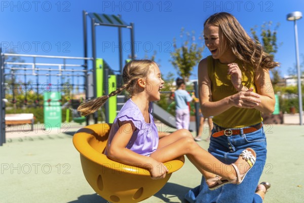 Mother and daughter bonding, laughing, and playing together on a sunny outdoor playground, enjoying a moment of happiness and family fun during childhood