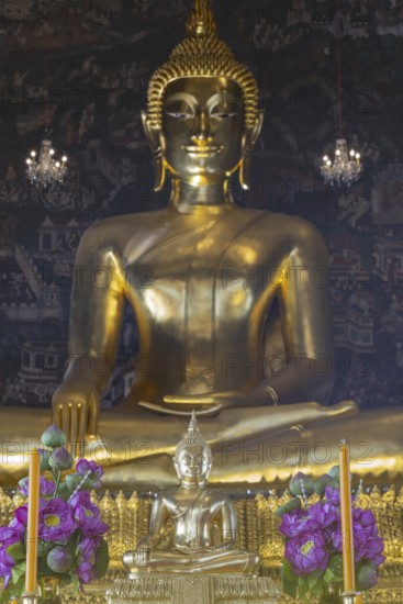 Golden Buddha statue, Phra Buddha Trilokachet surrounded by crystal chandeliers and exquisite wall paintings, interior view of Phra Ubosot or ordination hall, Wat Suthat Thepwararam, Royal Temple, Phra Nakhon, Bangkok, Thailand