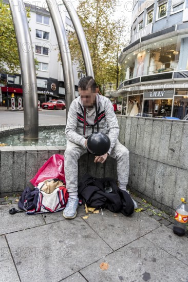 Man in public consumes laughing gas filled into a balloon with a gas cartridge, still legal intoxicant, pedestrian zone in Essen, North Rhine-Westphalia, Germany