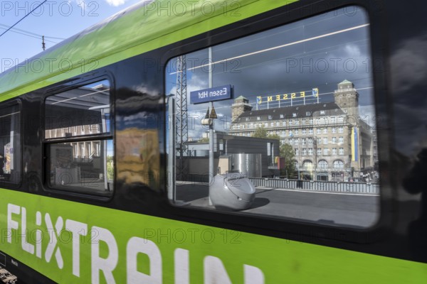 Flixtrain train on track 2 in Essen main station, reflection of the Handelshof building, city, platform in the window of the train, North Rhine-Westphalia, Germany