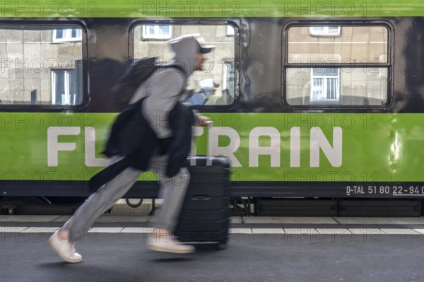 Flixtrain train on track 2 in Essen main station, passenger runs with luggage to reach his train, North Rhine-Westphalia, Germany