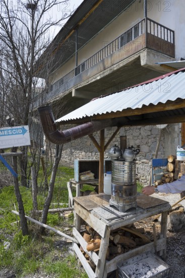 Metal oven with tea kettles in a courtyard with buildings and stacks of wood, traditional samovar, kettle for making tea, powered by wood, on the side of the road on the D200 near Imranli, Sivas province, Turkey