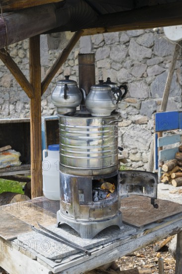 Wood-fired metal stove with tea kettles and wood supply on a table, traditional samovar, kettle for making tea, powered by wood, on the side of the road on the D200 near Imranli, Sivas province, Turkey