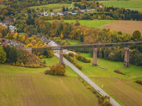 Railway bridge over an autumnal valley with colorful trees and a small village, Dornstetten, Freudenstadt district, Germany
