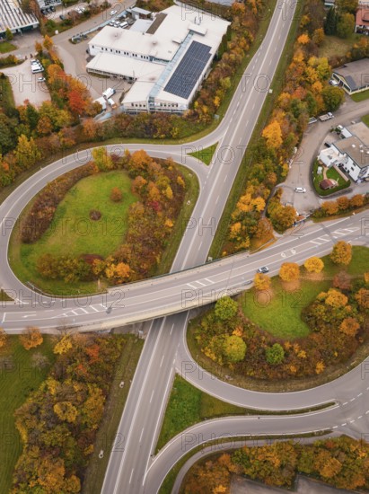 Road intersection with roundabout surrounded by green areas and autumn trees from a bird's eye view, Dornstetten, Freudenstadt district, Germany
