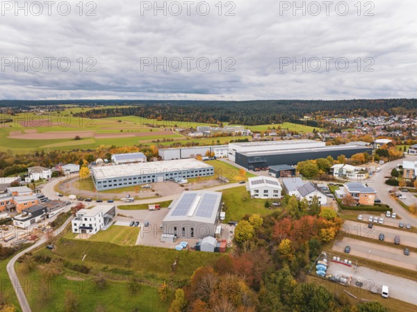 Industrial buildings surrounded by fields and trees in autumn colors under cloudy sky, Dornstetten, Freudenstadt district, Germany