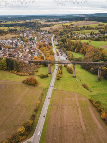 River and road criss-cross autumnal landscape with bridge and nearby village, Dornstetten, Freudenstadt district, Germany